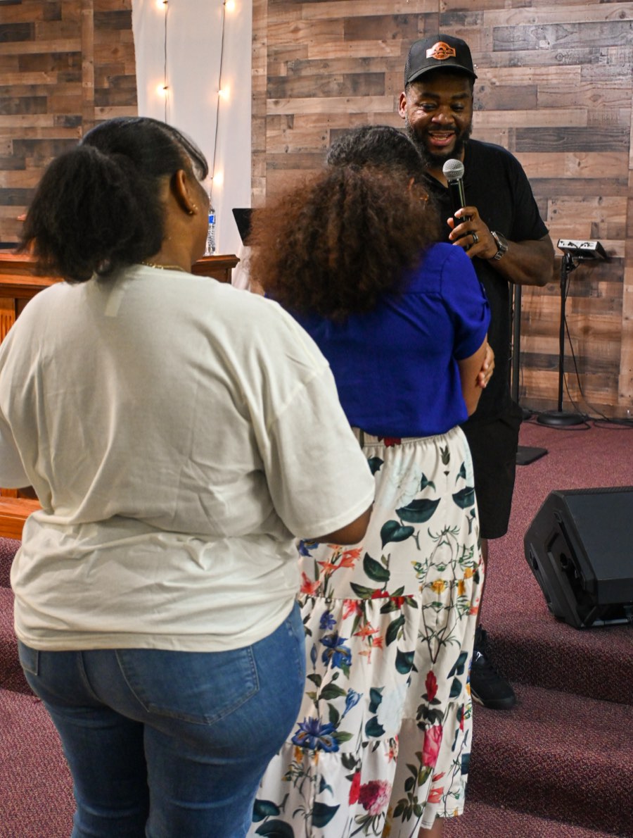 The pastor smiling and talking with two women after the service.