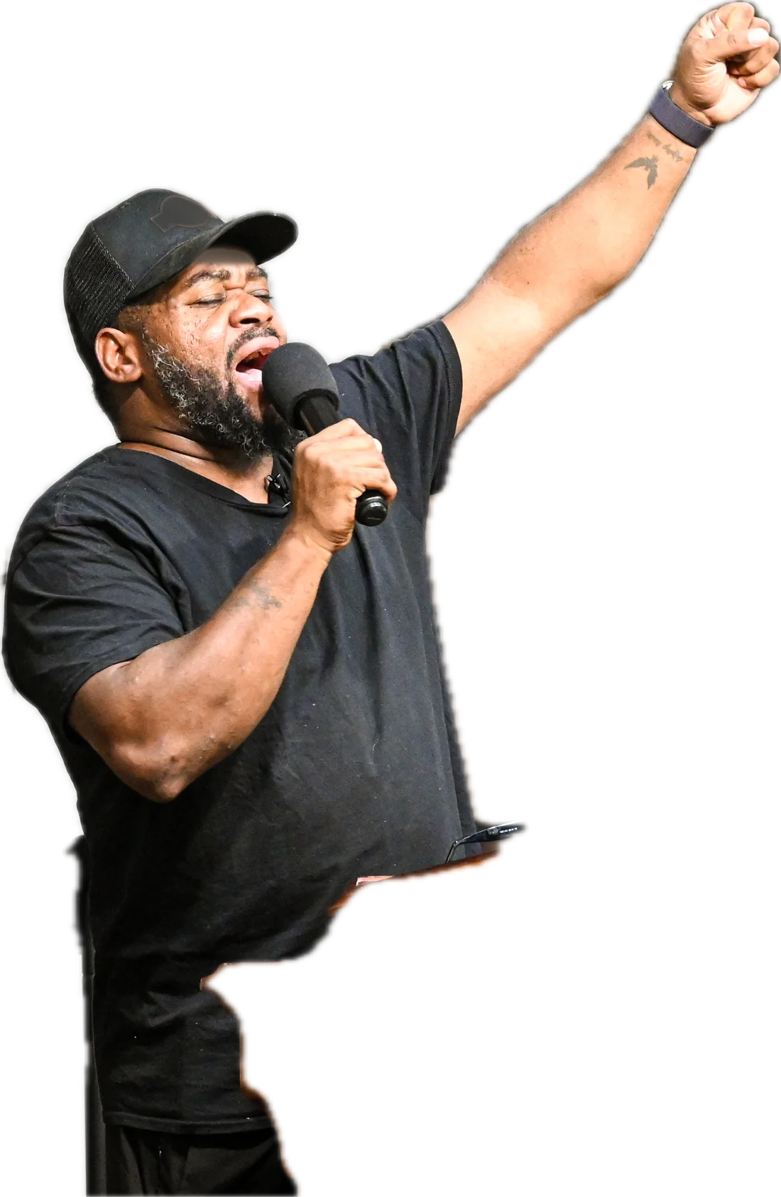 The pastor preaching with a microphone, one fist raised.